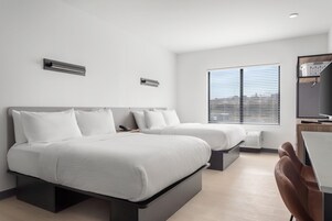 Una habitación de hotel moderna con dos camas, un escritorio y una ventana con persianas.
