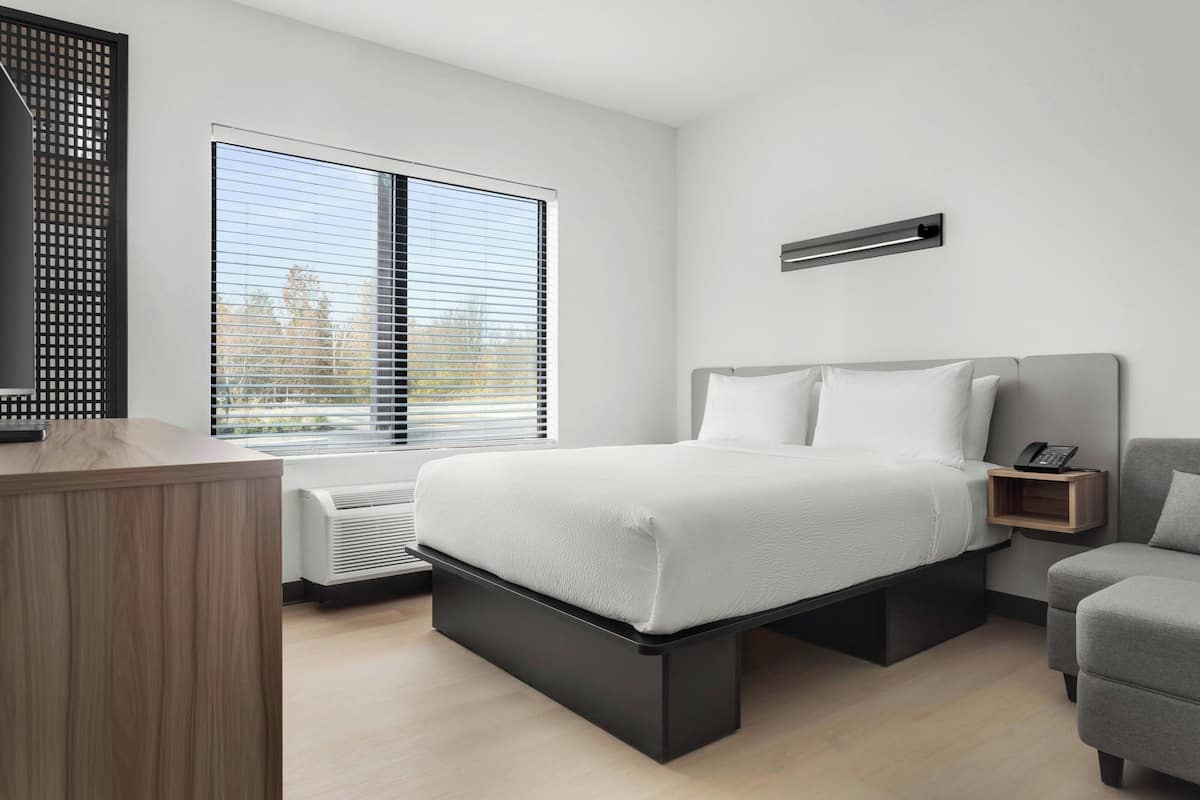 Un dormitorio moderno con cama, mesita de noche y escritorio.
