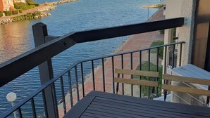 Un balcone con vista su un fiume, un vialetto in mattoni e un edificio con una torre dell'orologio.