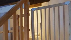 Una scala in legno con ringhiera che conduce a una camera da letto con un letto e un comodino.