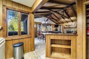 A wooden interior with a kitchen, dining area, and a view through a window. - Ruby Retreat – Mountain Views, 2 Decks, Fire Pit, Creek, Fast WiFi, Generator (Franklin)
