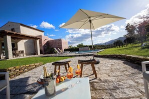 An outdoor patio with a table set for a meal, a bottle of champagne, and glasses of wine.
