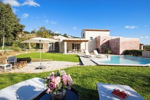 A modern house with a swimming pool, outdoor seating, and a garden.