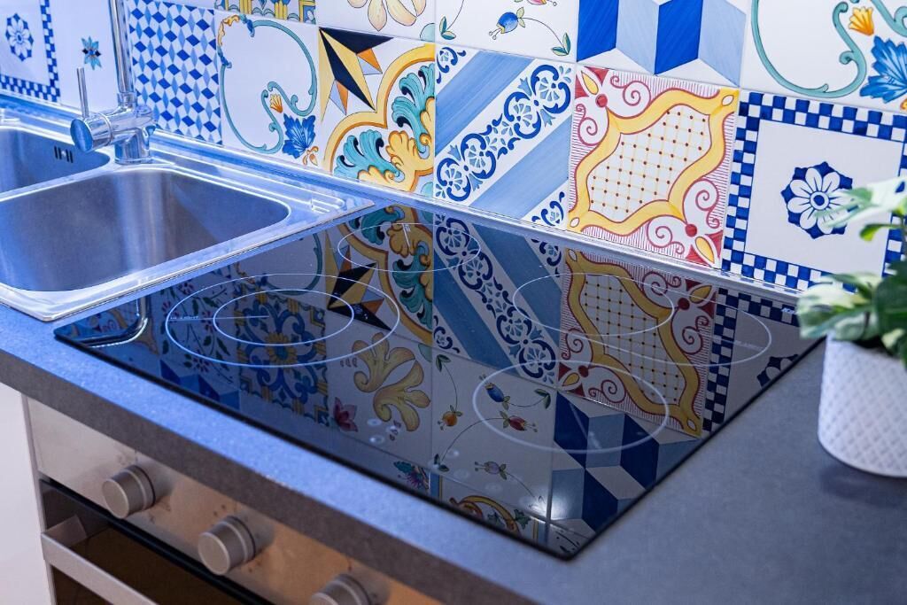 Una cucina con un lavello moderno in acciaio inossidabile e un backsplash colorato.