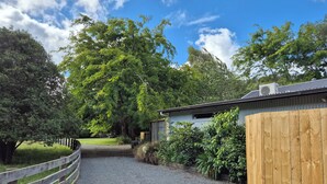 A gravel driveway leading to a wooden fence and a corrugated metal building.