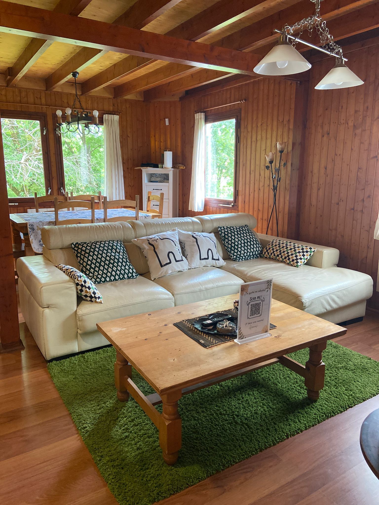 Uma sala de estar aconchegante com um sofá, uma mesa de centro de madeira e um tapete verde.