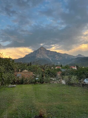 Un paysage de montagne avec un sommet imposant, un premier plan herbeux et un ciel nuageux.