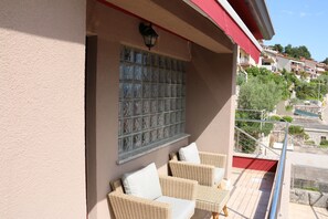 Un balcone con mobili in vimini e un pannello di vetro decorativo.