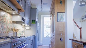 Une cuisine avec des meubles de rangement en bois, un four encastré et un plan de travail avec une plaque de cuisson.