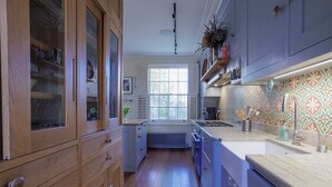 Une cuisine avec des meubles en bois, une fenêtre et un crédence décorée.