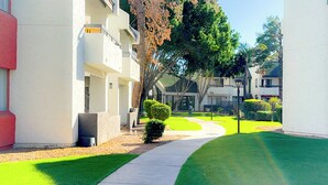 A pathway leading to a building with a white facade and multiple balconies. - Designer Resort Style - 1 King Bed Apartment, Pool, Gym in beautiful Gilbert AZ (Gilbert)