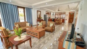 A spacious living area with a sofa set, a coffee table, and a TV stand with a remote control. - LA BELLE RESIDENCE (Mahe Island)