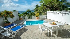 A poolside area with a pool, lounge chairs, and a table with a fruit tray. - LA BELLE RESIDENCE (Mahe Island)