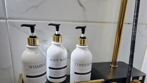 A bathroom vanity with three bottles of body wash and a red bottle of hand sanitizer. - Seaview & City Lights Retreat, Marine City (Busan)