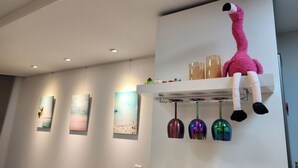 A modern interior with wall-mounted art, a shelf with a plush toy and glasses, and hanging decorative lights. - Seaview & City Lights Retreat, Marine City (Busan)