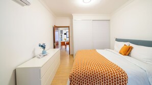 Un dormitorio con cama, cómoda, espejo y armario.