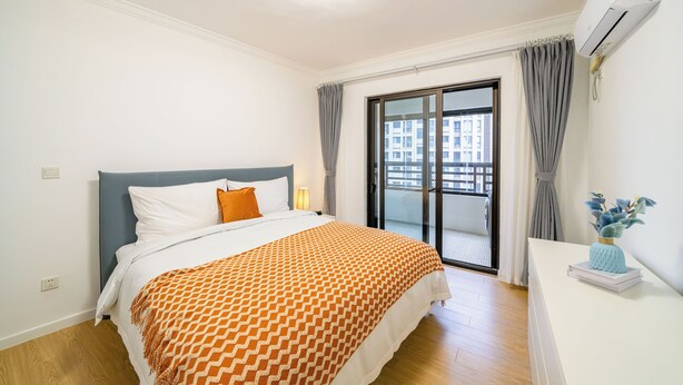 Habitación de hotel con cama, mesita de noche, aire acondicionado y vistas al exterior.