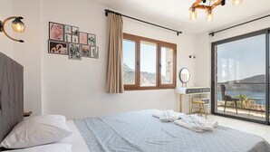 Ein Schlafzimmer mit Bett, Schreibtisch, Stuhl und einem großen Fenster mit Blick.