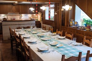 Un comedor con una mesa larga dispuesta para una comida, armarios de madera y un ventanal con vistas.