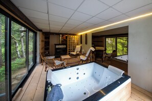 Habitación con una bañera grande, muebles de mimbre y vistas al bosque.
