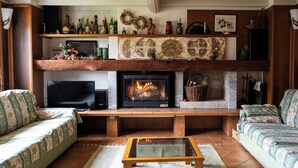 Ein Wohnzimmer mit Kamin, Fernseher, Sofa und Couchtisch.