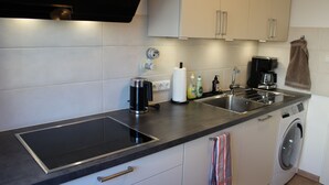 A modern kitchen with a built-in stove, a coffee maker, a washing machine, and a sink. - At Biebrich Palace Park (Wiesbaden)