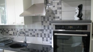 A modern kitchen with a stainless steel oven, a black countertop, and a tiled backsplash.