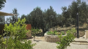 A garden with gravel paths, a stone planter with flowers, and a brick wall.