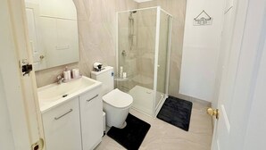 A modern bathroom with a glass-enclosed shower, a white toilet, and a vanity with a mirror. - Quiet Farm-style Retreat With Scenic Views (Durham Lead)
