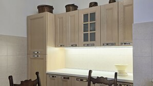 A kitchen with wooden cabinets, a white countertop, and a dining table with chairs. - 60sqm downtown with garden | Casa Da Diego (Civitanova Marche)