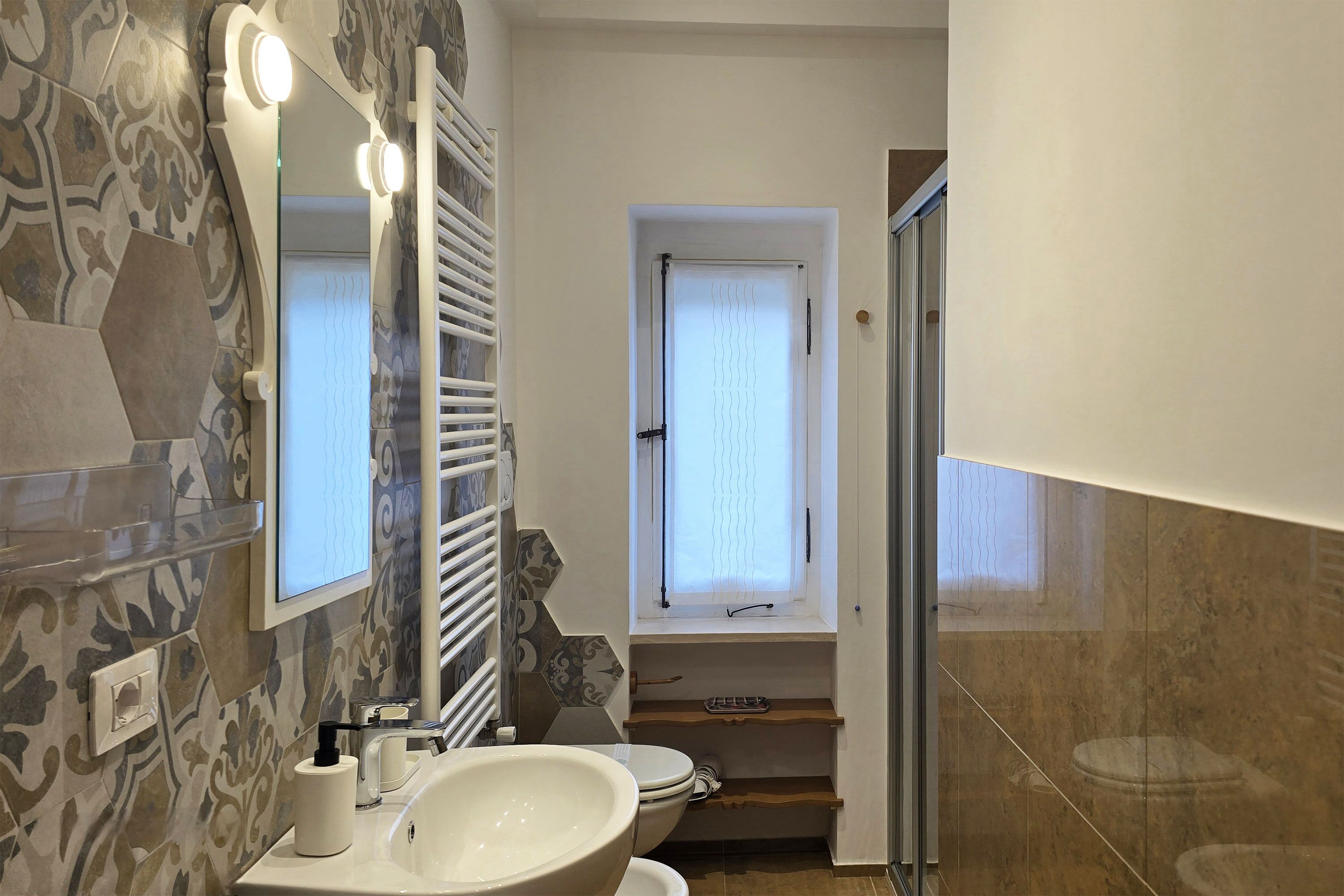 A bathroom with a large mirror, a sink, and a shower.