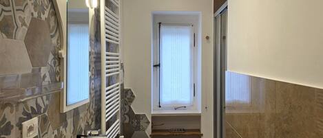 A bathroom with a large mirror, a sink, and a shower.