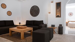 Ein modernes Wohnzimmer mit einer schwarzen Couch, einem Holztisch und einem gemusterten Teppich.