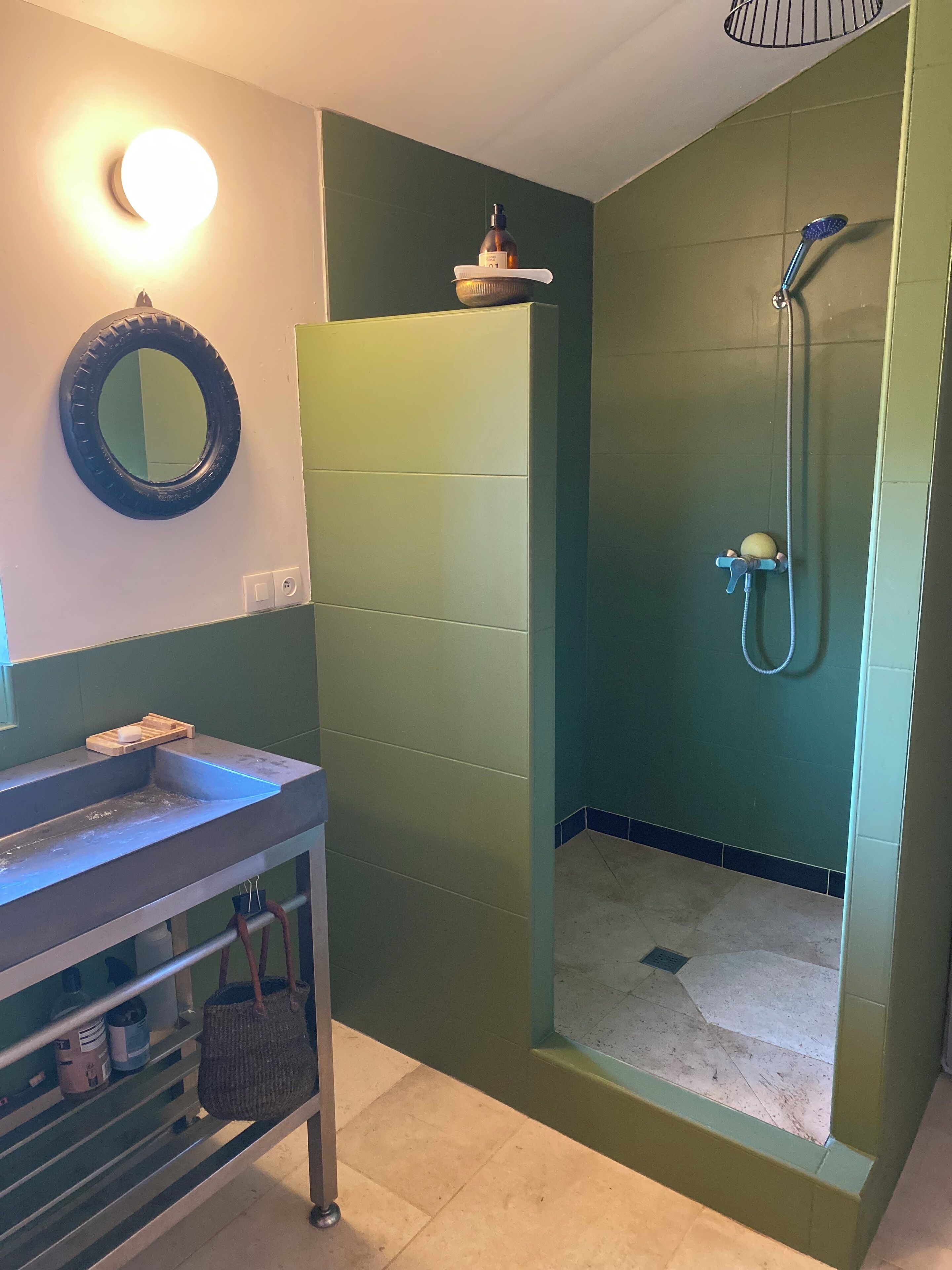 A bathroom with a green vanity, a mirror, a sink, and a shower enclosure.