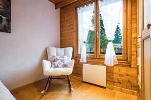A cozy room with wooden walls, a white radiator, and a rocking chair with a cushion. - Argentière 7p facing Aiguille du Midi Close to pistes (Chamonix-Mont-Blanc)