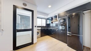 A modern kitchen with a built-in washing machine, a large refrigerator, and a microwave. - Seven Floors (Tunis)
