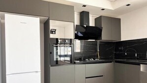 A modern kitchen with grey cabinetry, a black stove, and a black backsplash.