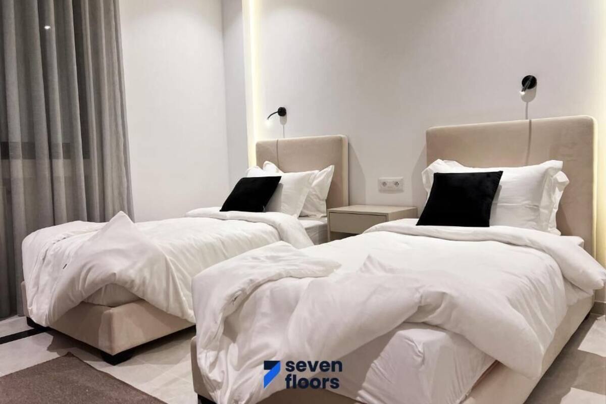 Habitación de hotel con dos camas, una mesita de noche y diseño moderno.