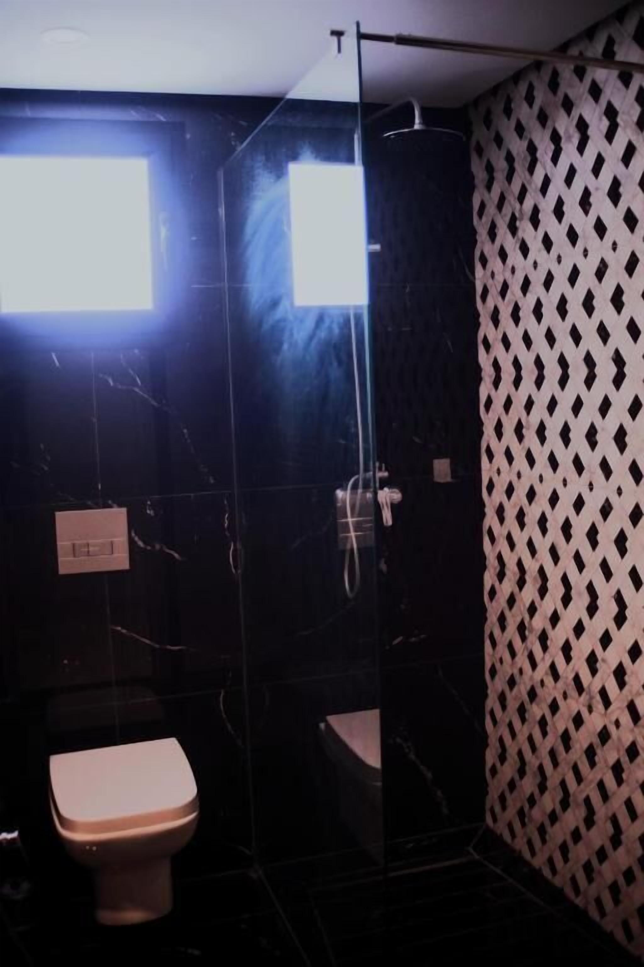 Un baño con inodoro, cabina de ducha y pared con estampado.