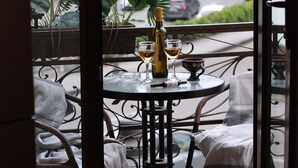 Een balkon met een eettafel, inclusief een fles en glazen.