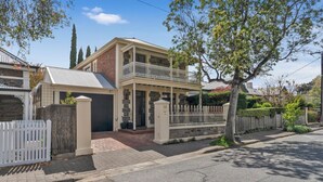 Una casa a due piani con un balcone, un garage e un vialetto recintato.