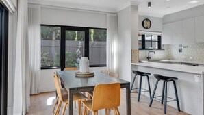 Una cucina moderna con zona pranzo, caratterizzata da un'ampia finestra, una ventola a soffitto e un orologio a parete.