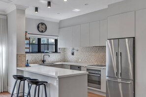 A modern kitchen with a central island, stainless steel appliances, and a large window. - Parkside Haven - 4BR/2.5Bath + EV Charger (Parkside)