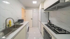 A modern kitchen with a stainless steel sink, a built-in washing machine, a stove, and a refrigerator. - Tyms 3BR 2BA Apt  Gubei Fully Furnished (Shanghai)