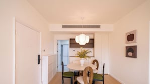 A dining area with a round table, four chairs, a hanging light fixture, and a potted plant. - Tyms 3BR 2BA Apt  Gubei Fully Furnished (Shanghai)