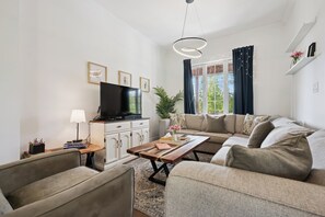 A modern living room with a sofa, coffee table, TV, and decorative items.