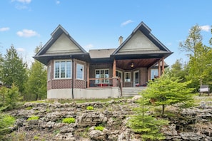 A two-story house with a brick exterior, a covered porch, and a stone retaining wall.