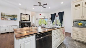 Una cocina moderna con una isla central, armarios blancos, lavavajillas y ventilador de techo.