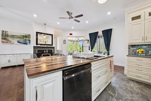 A modern kitchen with a central island, white cabinetry, a dishwasher, and a ceiling fan.