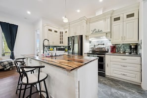 A spacious kitchen with white cabinetry, a central island, and a built-in stove.